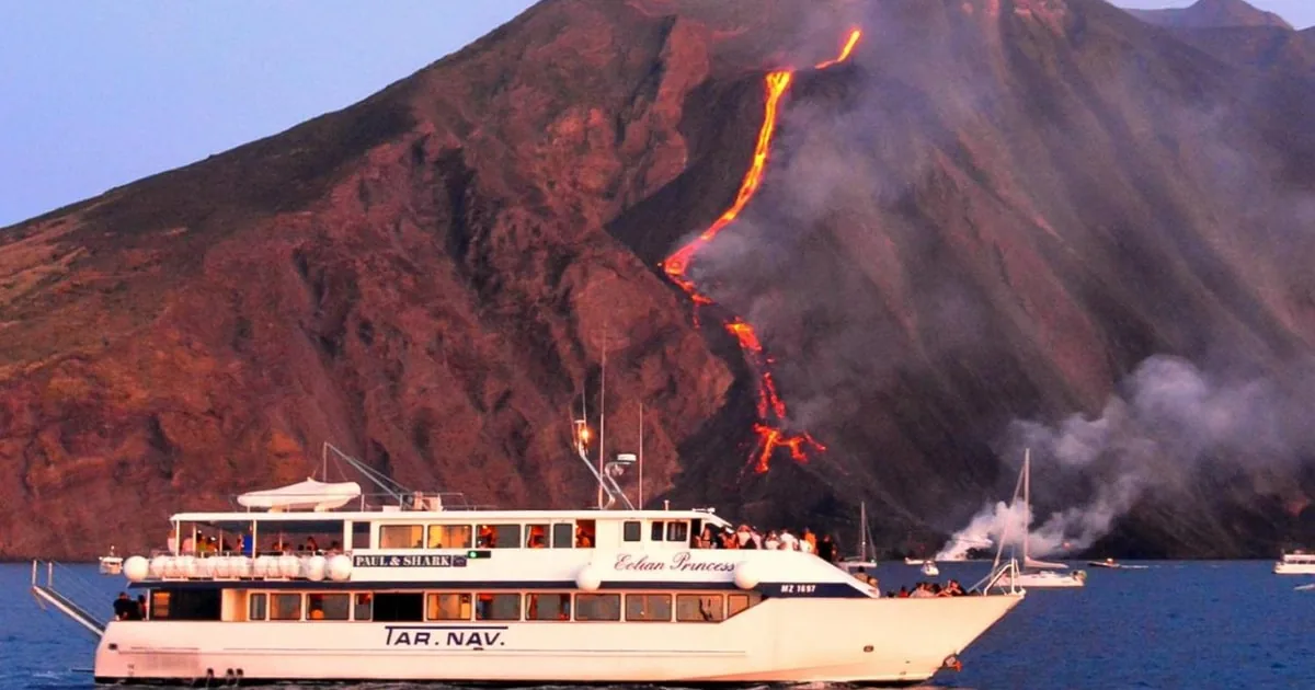 Passenger boat anchored off Stromboli island at dusk waiting for the volcano eruptions on a boat trip by night from Milazzo, Aeolian Islands, Italy